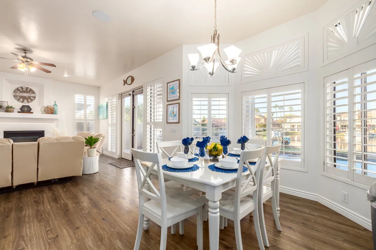 A spacious dining area with a table accented in blue, comfortable seating, and large windows overlooking the water. The view creates a bright, uplifting ambiance, perfect for group meals or casual relaxation.