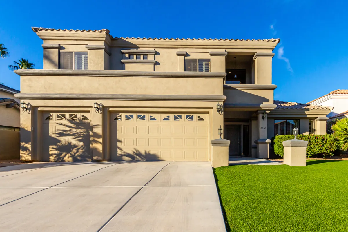 The image showcases an inviting exterior with a two-car garage, landscaped front yard, and detailed architectural elements. It indicates an easily accessible and upscale environment for executive groups.
