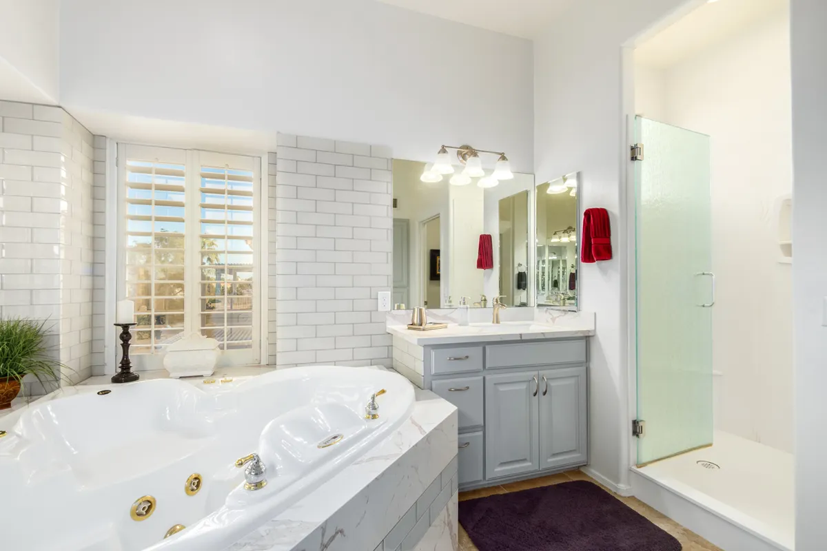 A spa-inspired bathroom featuring a luxurious bathtub, dual sinks, large mirrors, and a glass shower. The space is bright, modern, and exudes a sense of calm and relaxation.